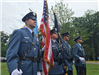 Four officers in a line in dress uniform carrying flags