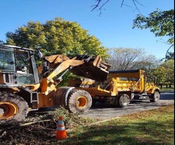 Heavy Tractor with claw picking up brush along street