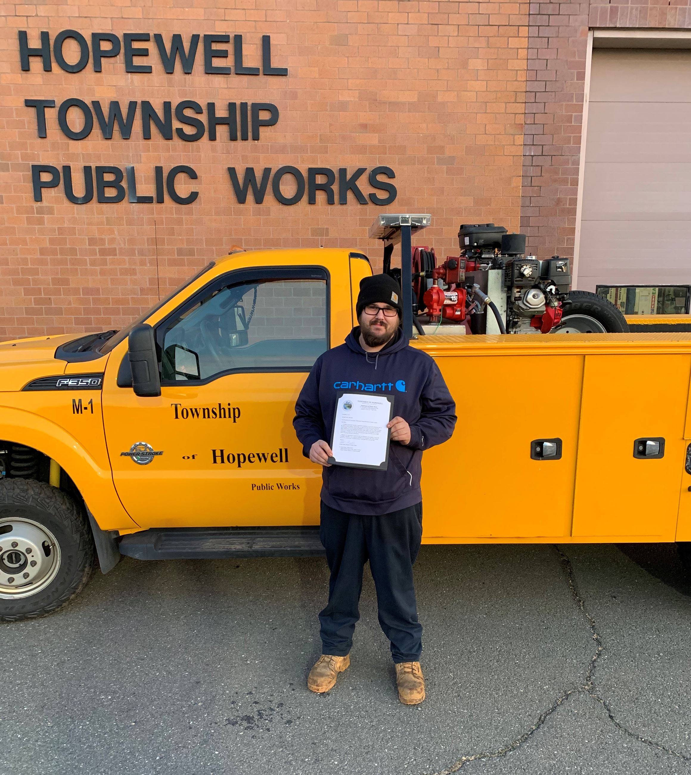 Public Works Mechanic Mike Elonis in front of truck with certificate of recognition