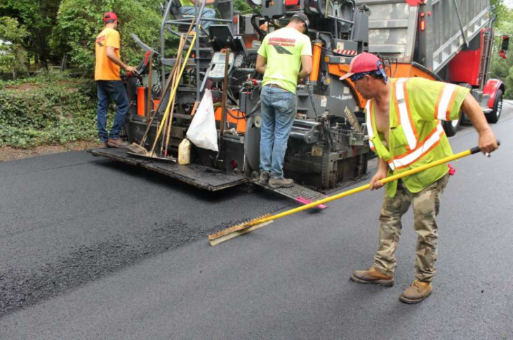Guys paving road with large truck