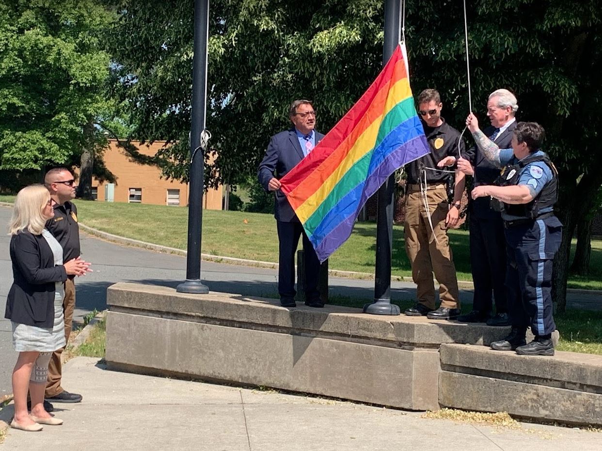 Police, the mayor, and Assemblyman Anthony Verrelli raise the pride flag up to flagpole at municipal