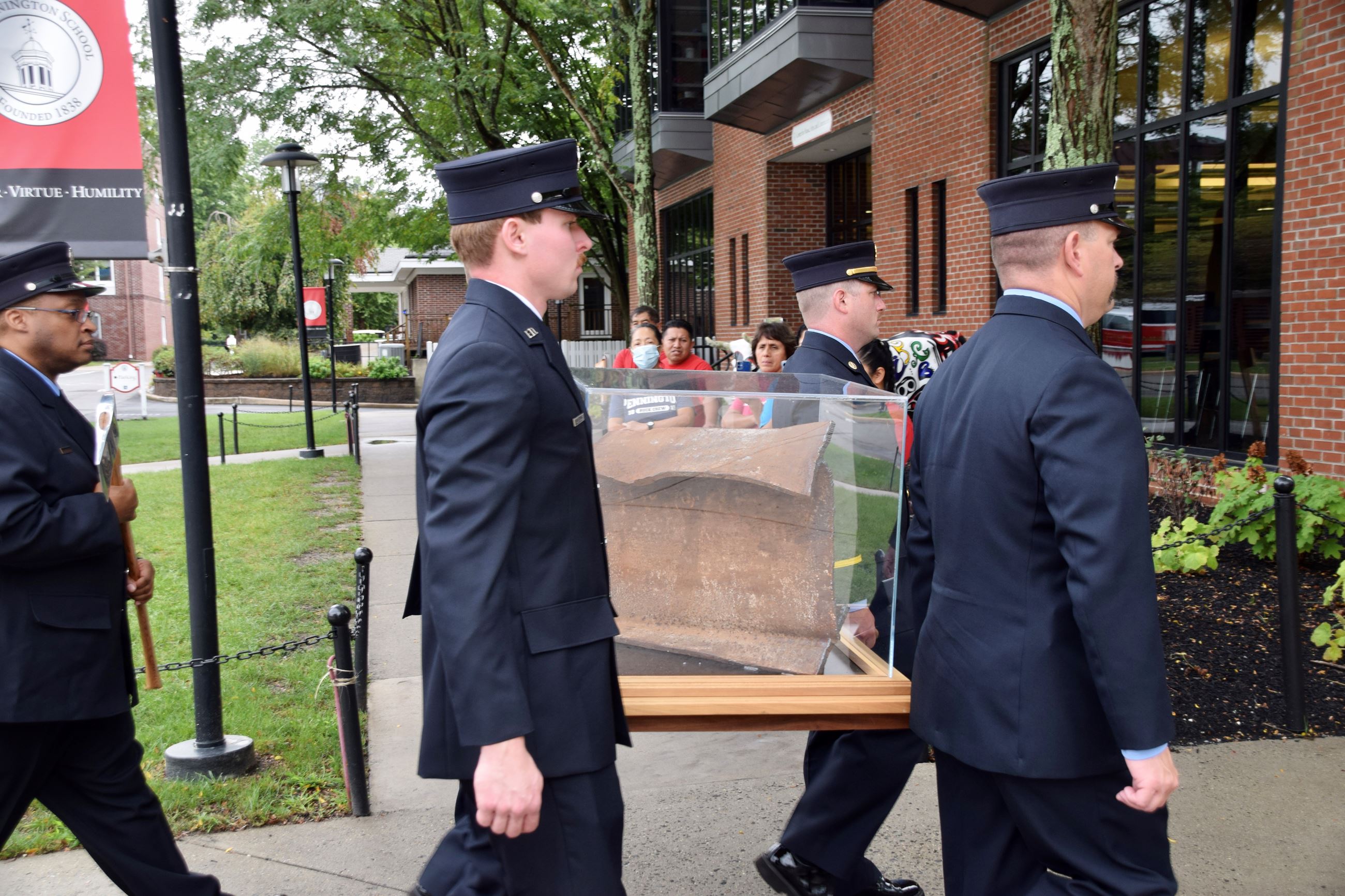 Photo of 4 firefighters carrying a piece of steel from the World Trade Center in a plexiglass box