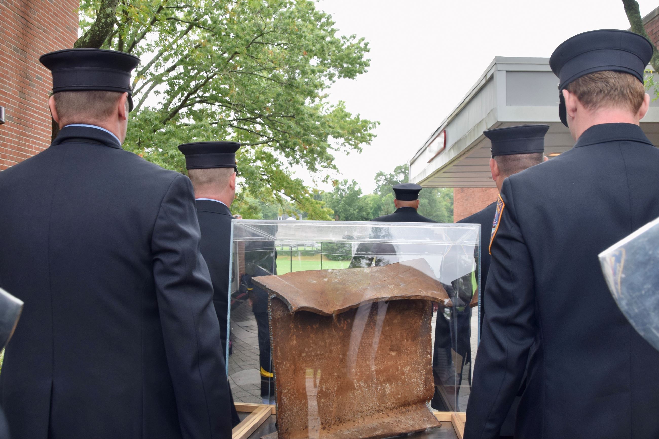 Rear view Photo of 4 firefighters carrying a piece of steel from the World Trade Center in a box